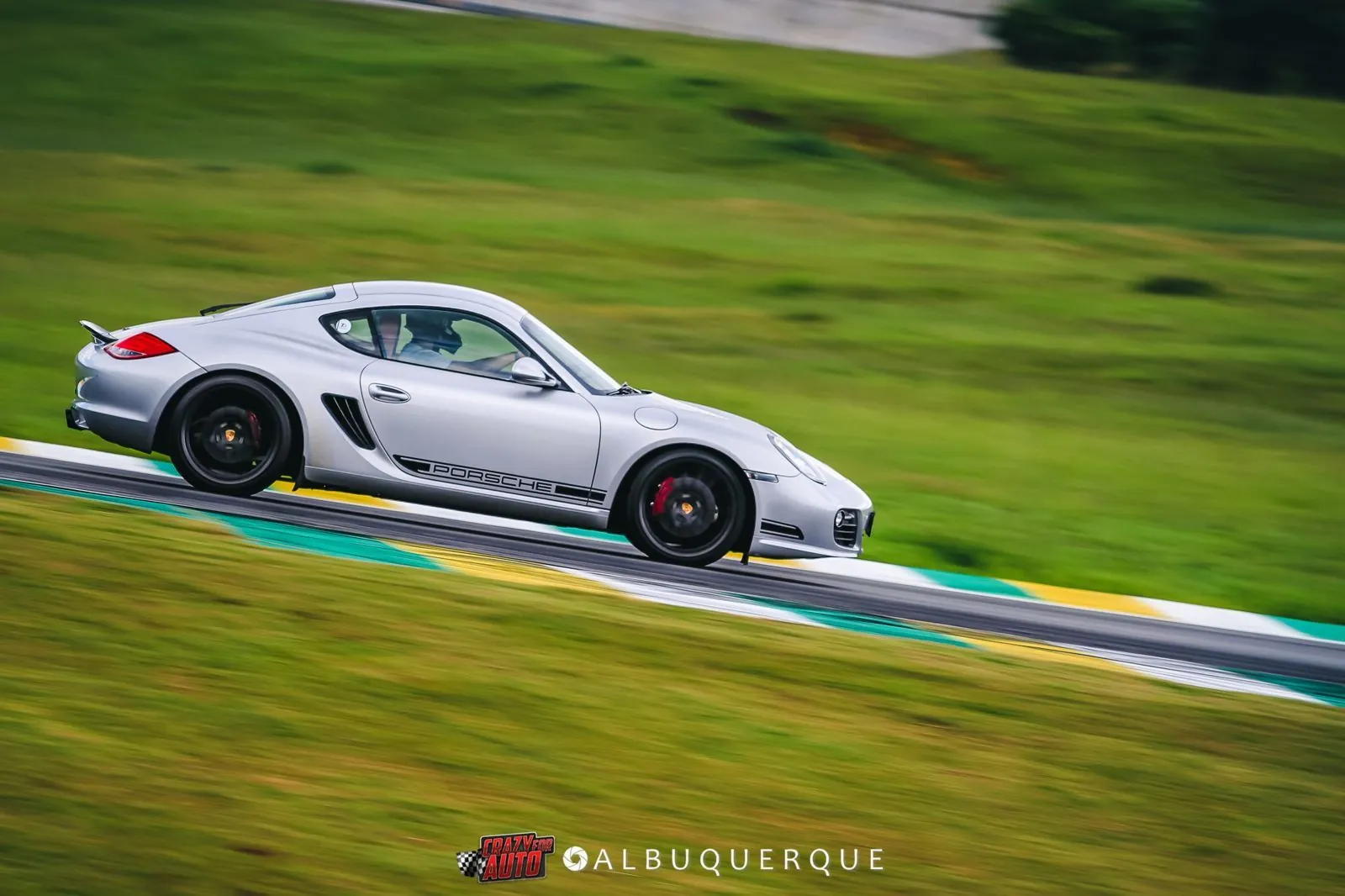 Porsche Cayman prata em movimento, com a grama ao fundo