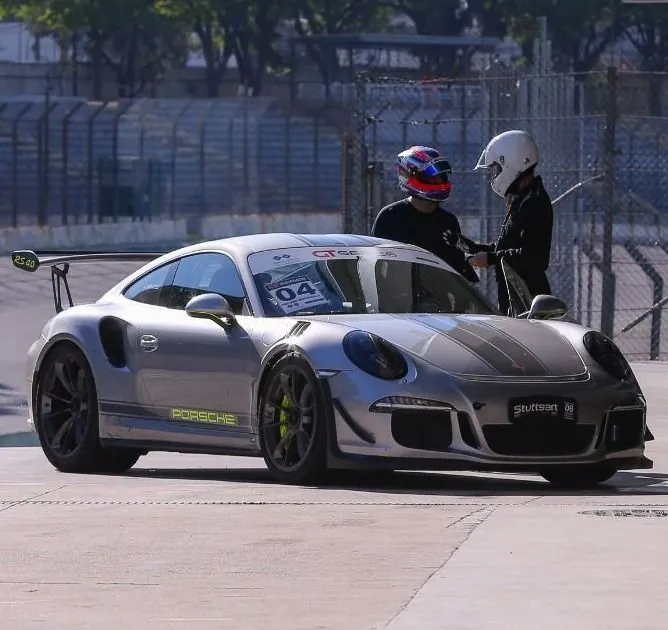 Instrutor e aluno ao lado de um Porsche 911 GT3 RS nos boxes
