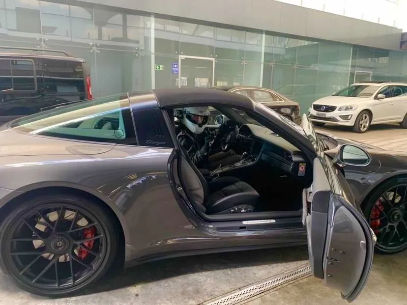 Aluno de capacete ao volante de um Porsche 911 Targa