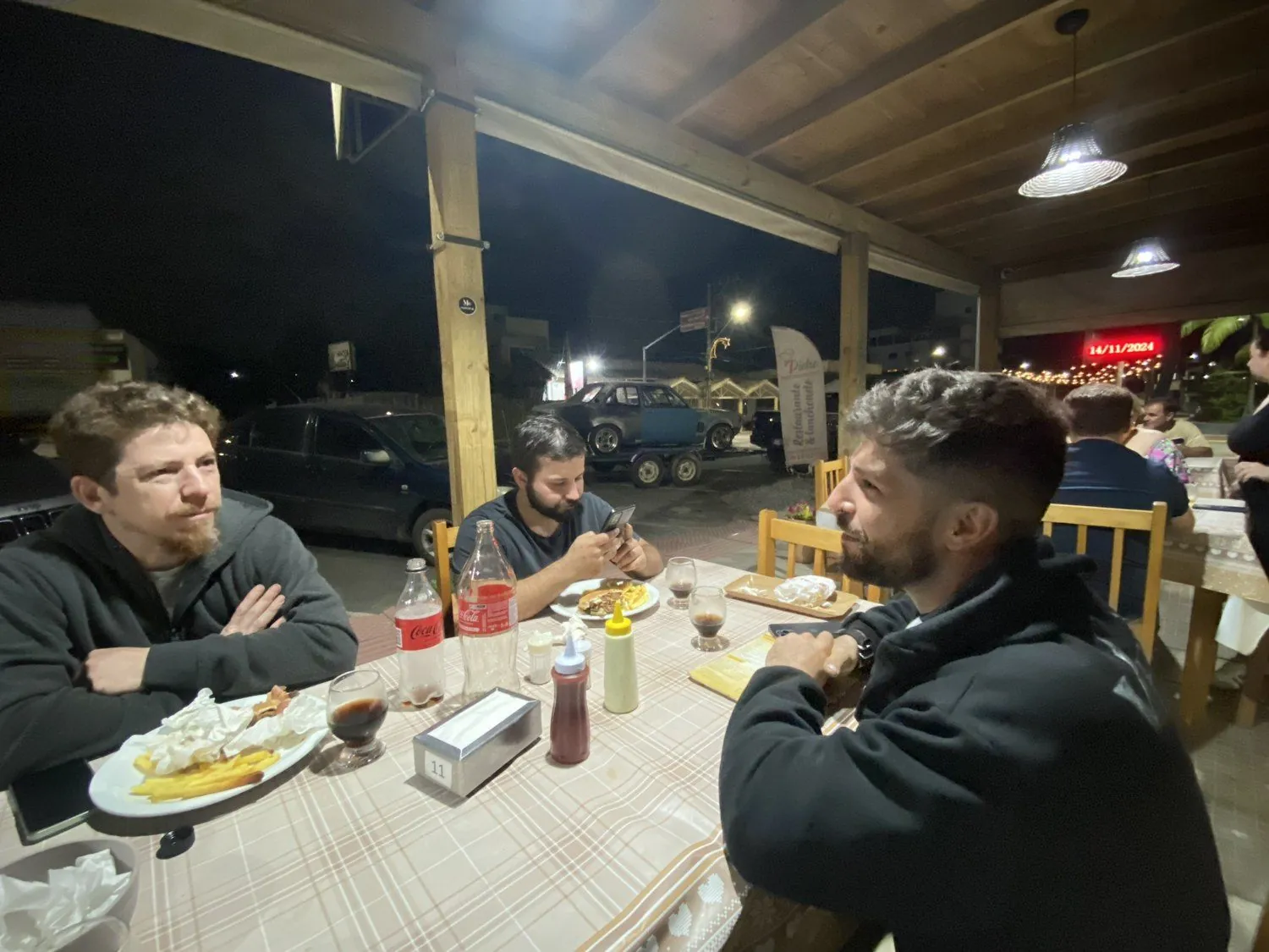 Amigos da viagem jantando à noite na véspera da subida da Serra do Rio do Rastro, com o CHEV37TE na carretinha ao fundo