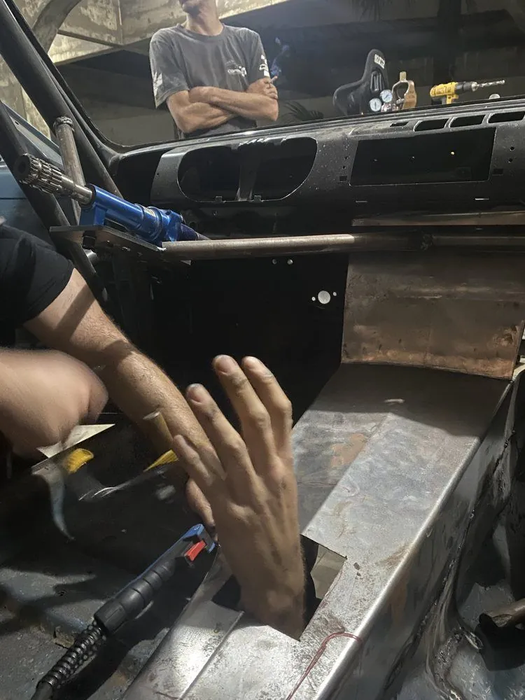 Mão saindo por um recorte no assoalho do CHEV37TE durante os trabalhos de solda