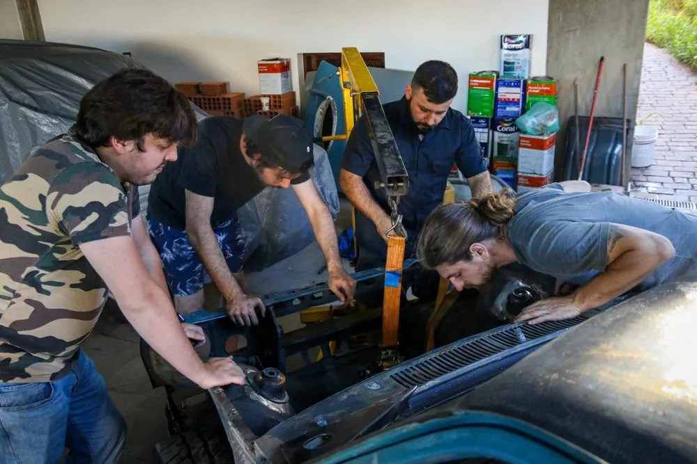 Quatro amigos em volta do cofre do CHEV37TE posicionando o motor com o guincho