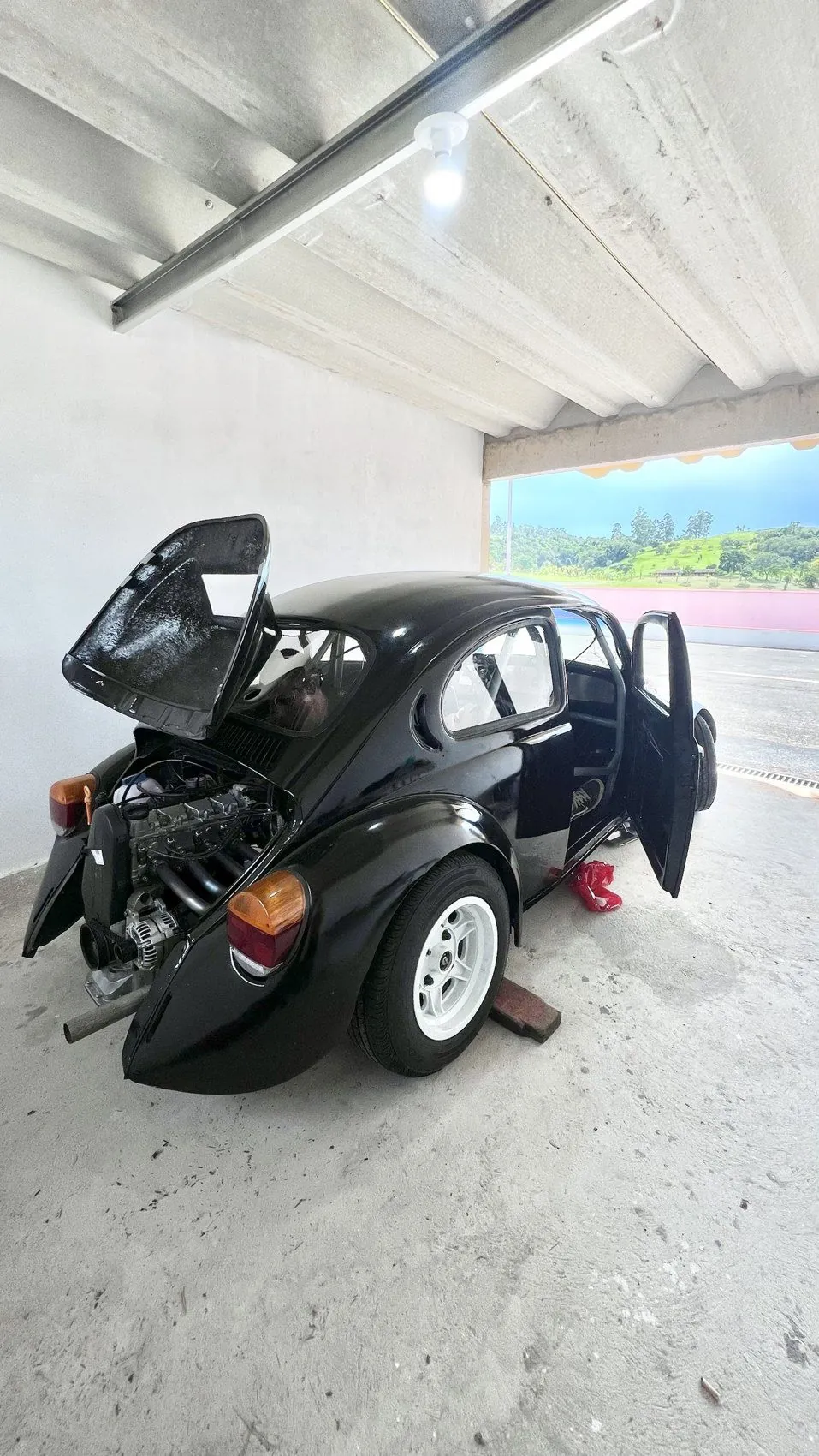 Fusca 37 todo preto, com o capô do motor aberto e o motor EA111 à mostra, no box da Fazenda Dimep