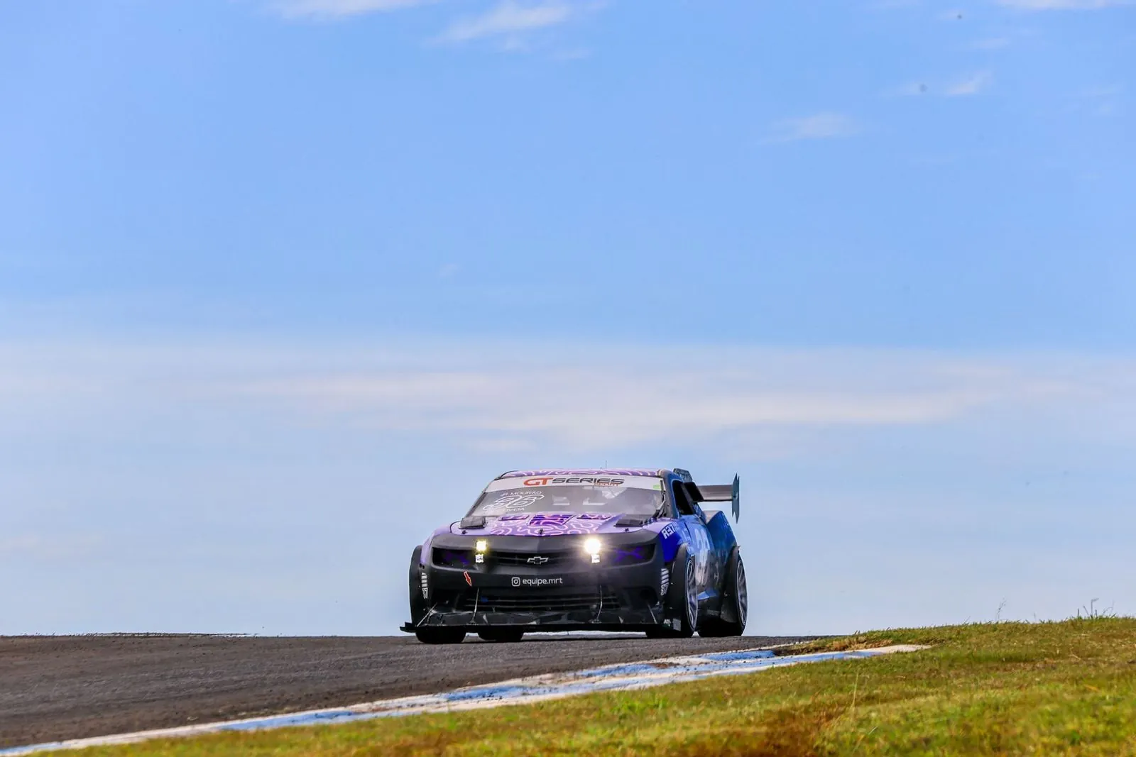 Camaro The Chaser número 36 no alto de uma subida, com o céu azul ao fundo