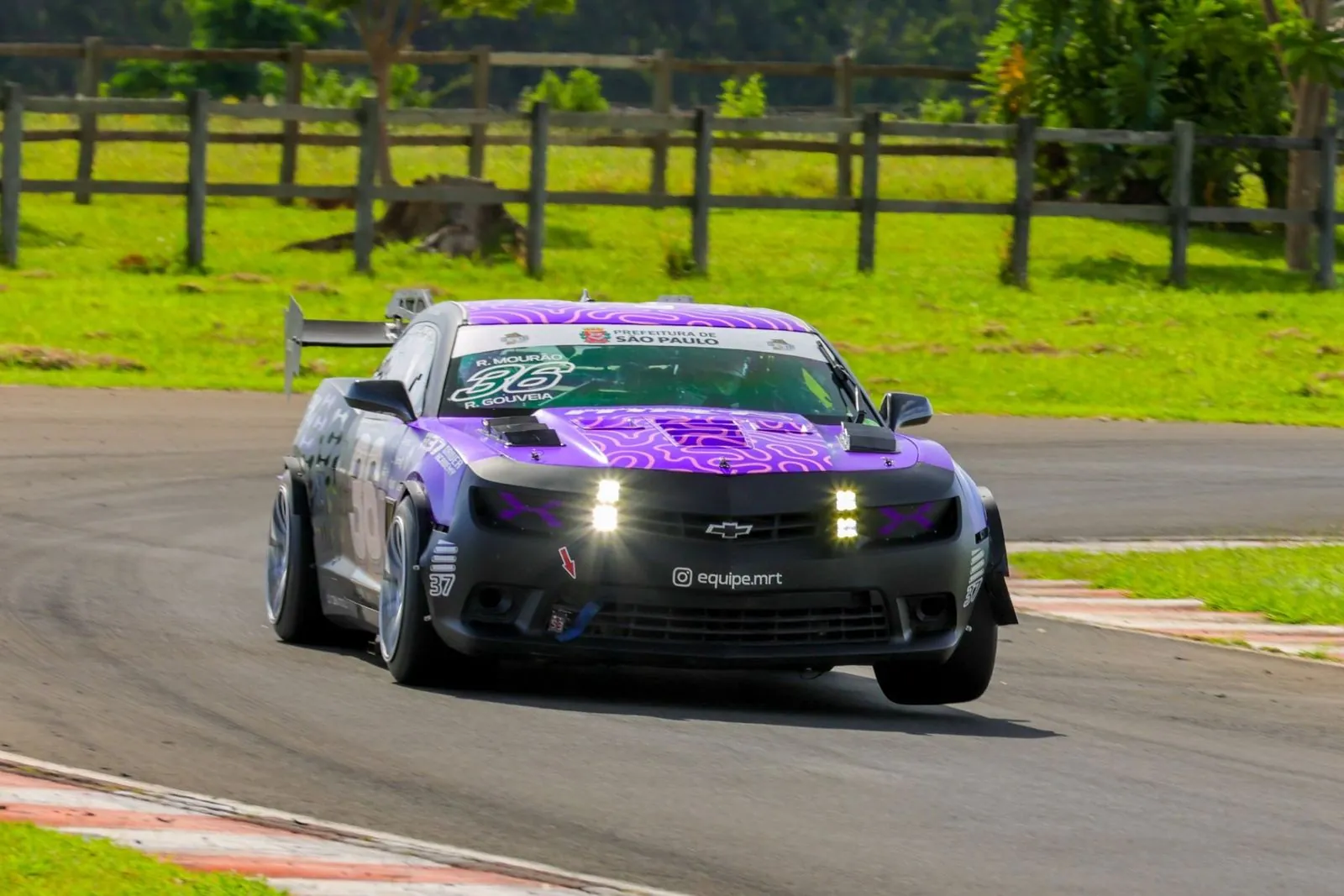 Camaro 36 em curva, com cerca de madeira ao fundo