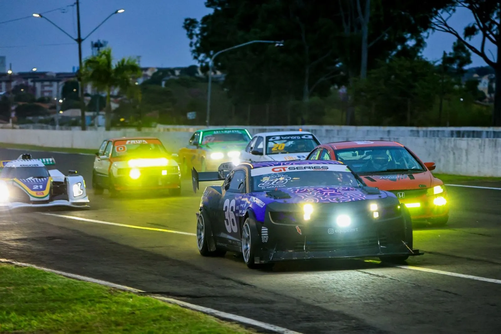 Camaro 36 liderando um pelotão ao entardecer, em prova da GT Series