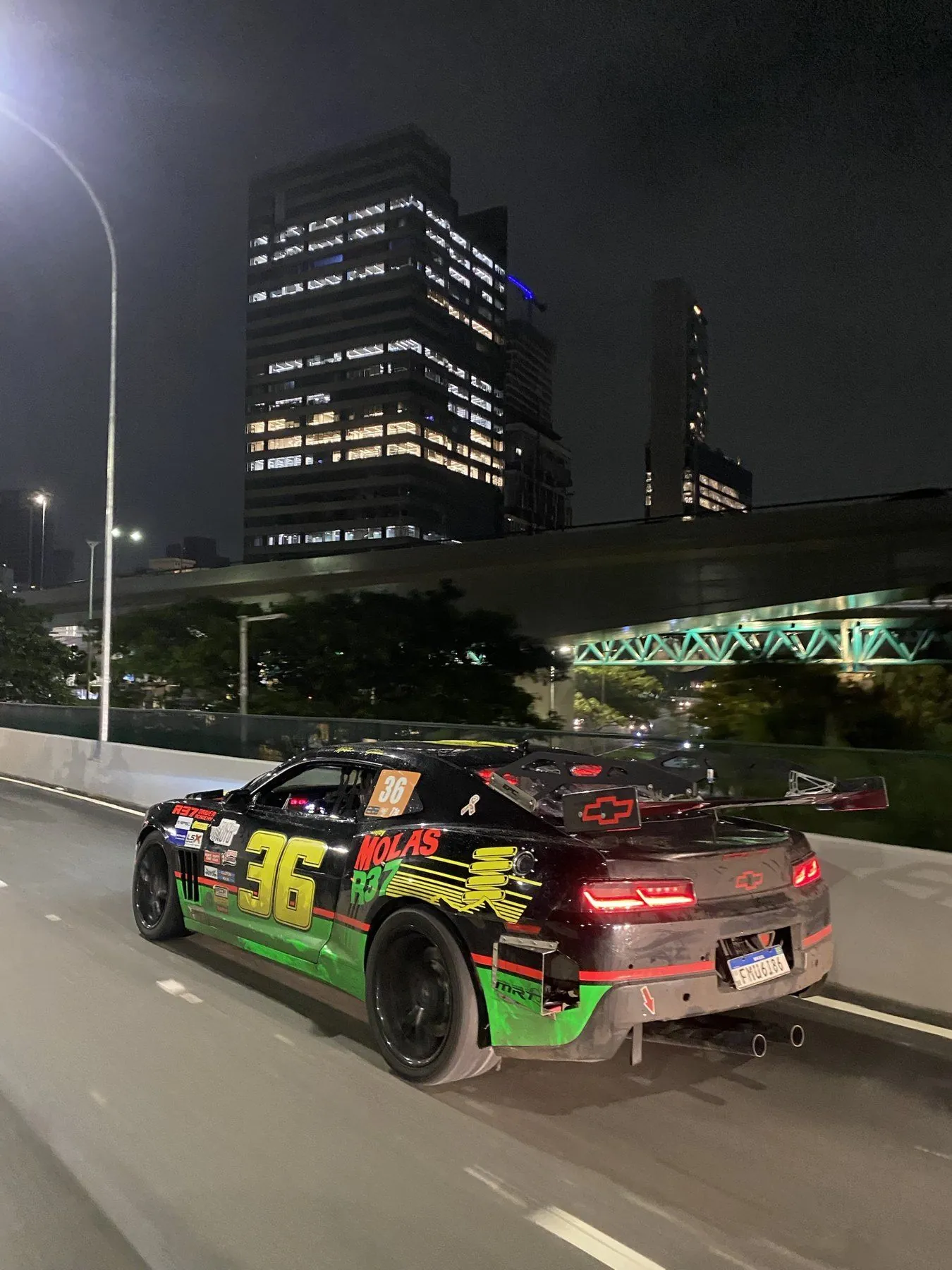 Camaro The Chaser número 36 rodando à noite por um viaduto de São Paulo, com prédios iluminados ao fundo