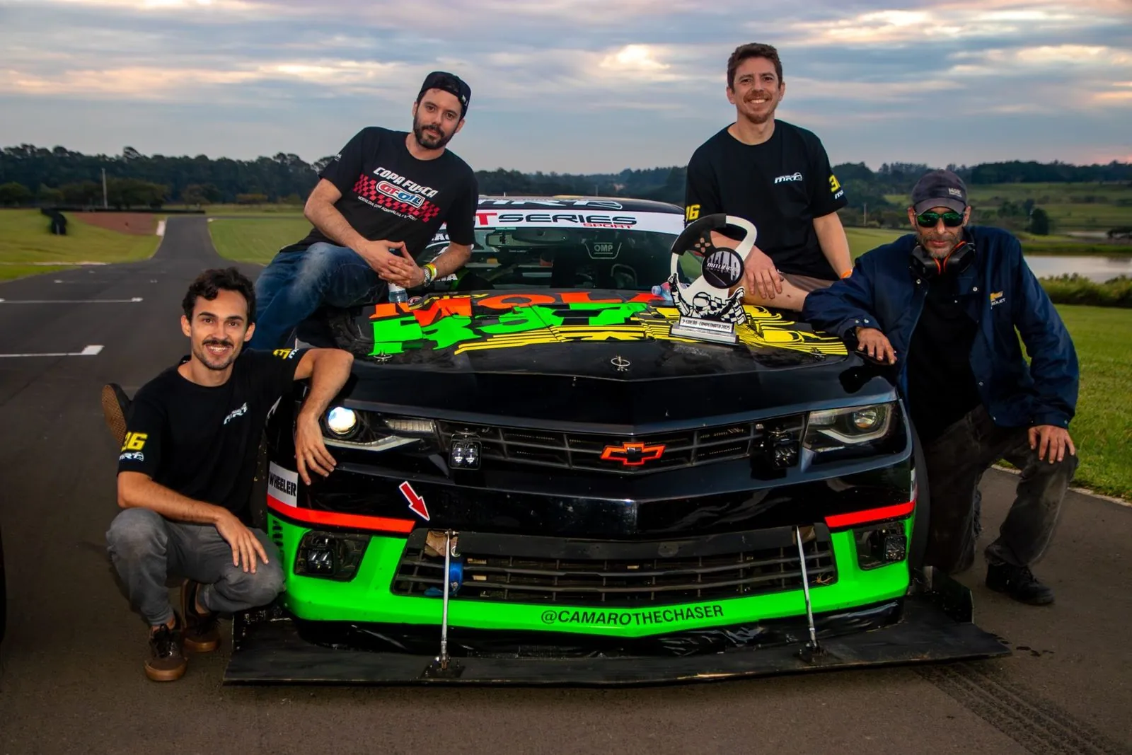 A equipe MRT reunida em volta do Camaro com a pintura da Molas R37 e um troféu sobre o capô
